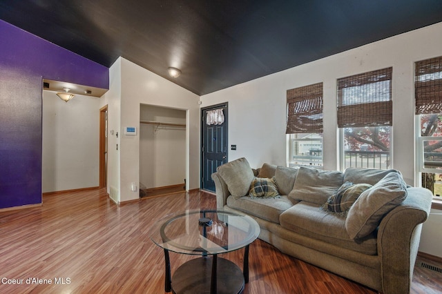 living room with healthy amount of natural light, wood finished floors, high vaulted ceiling, and baseboards