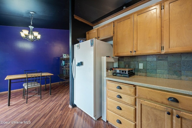 kitchen with freestanding refrigerator, a chandelier, light countertops, tasteful backsplash, and dark wood-style floors