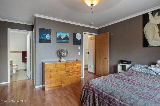 bedroom featuring wood finished floors, crown molding, baseboards, and ensuite bathroom