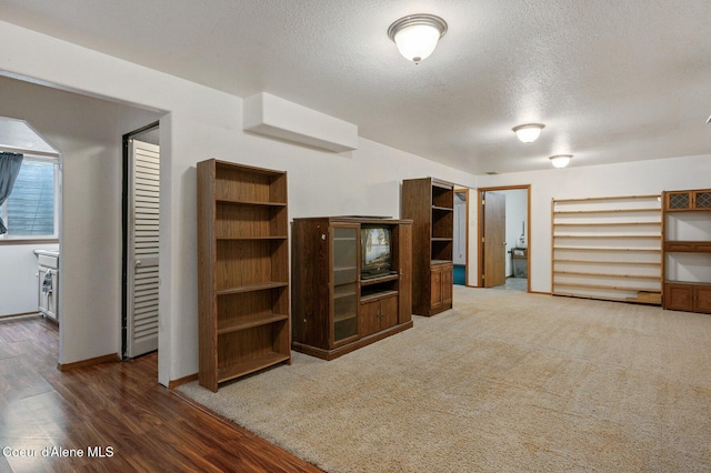 unfurnished living room featuring a textured ceiling and wood finished floors