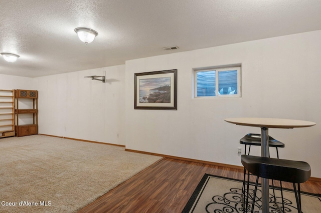 basement with a textured ceiling, wood finished floors, and baseboards
