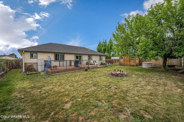 back of property with a fire pit, a storage shed, a deck, and an outdoor structure