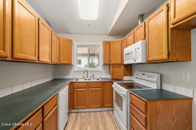 8694 N Clarkview Pl, Hayden Lake, ID 83835 - kitchen featuring white appliances, a sink, light wood-type flooring, dark countertops, and brown cabinets
