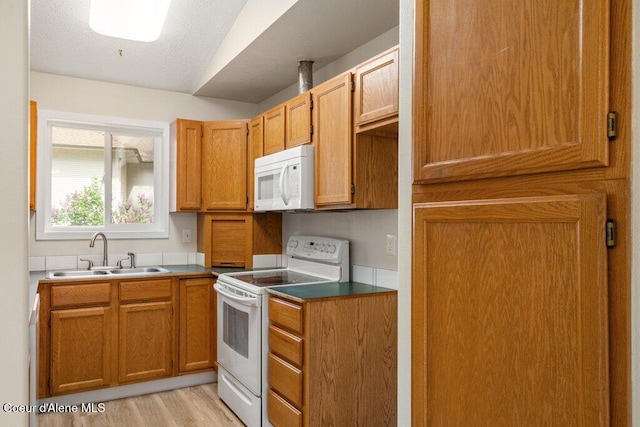 8694 N Clarkview Pl, Hayden Lake, ID 83835 - kitchen featuring white appliances, a sink, light wood-type flooring, and brown cabinetry