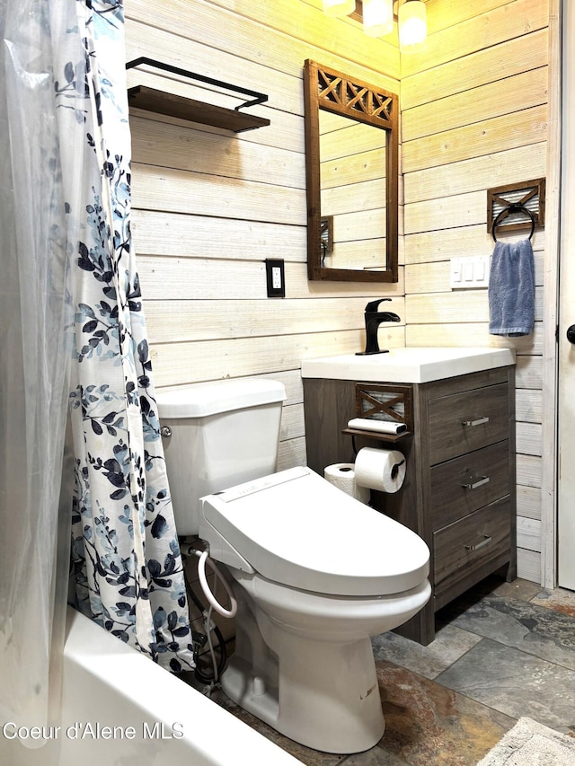 bathroom with wooden walls, toilet, stone finish flooring, vanity, and shower / bath combo