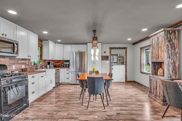 kitchen featuring stainless steel appliances, light wood-type flooring, a sink, tasteful backsplash, and recessed lighting