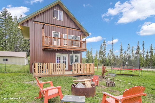 back of house with an outdoor fire pit, a trampoline, a deck, a balcony, and board and batten siding