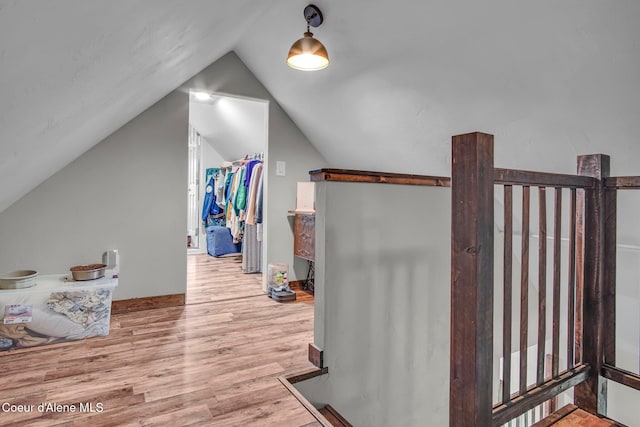 additional living space featuring wood finished floors and vaulted ceiling