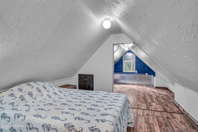 bedroom featuring a textured ceiling, wood finished floors, and lofted ceiling