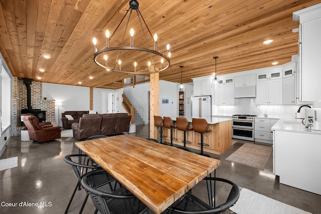 3298 W Coon Creek Rd, Plummer, ID 83851 - dining area with concrete floors, a wood stove, wood ceiling, stairs, and a chandelier