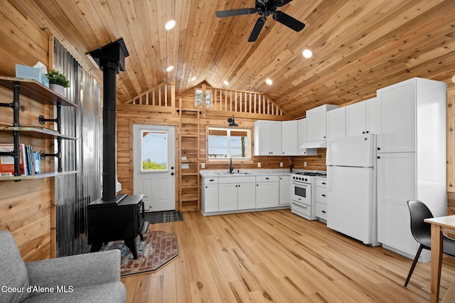 3298 W Coon Creek Rd, Plummer, ID 83851 - kitchen with white appliances, a wood stove, a sink, lofted ceiling, and light wood-style flooring