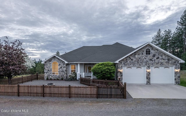 684 Chute Canyon Way, Bonners Ferry, ID 83805 - view of front of house with stone siding, concrete driveway, a garage, a fenced front yard, and roof with shingles
