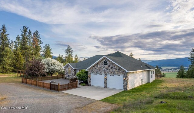 684 Chute Canyon Way, Bonners Ferry, ID 83805 - view of front of house featuring stone siding, concrete driveway, and a garage