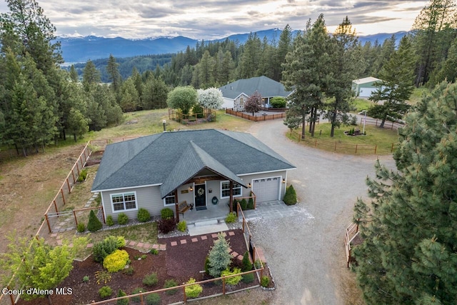 684 Chute Canyon Way, Bonners Ferry, ID 83805 - view of front facade with dirt driveway, a garage, a mountain view, and covered porch
