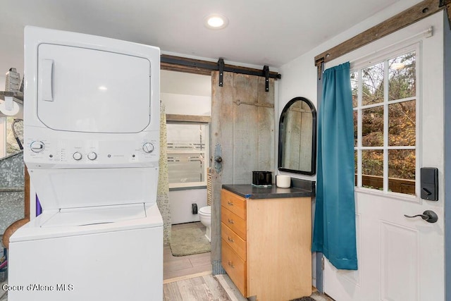 7547 W Channel Ln, Rathdrum, ID 83858 - laundry area featuring stacked washing machine and dryer, light wood-type flooring, a barn door, and recessed lighting