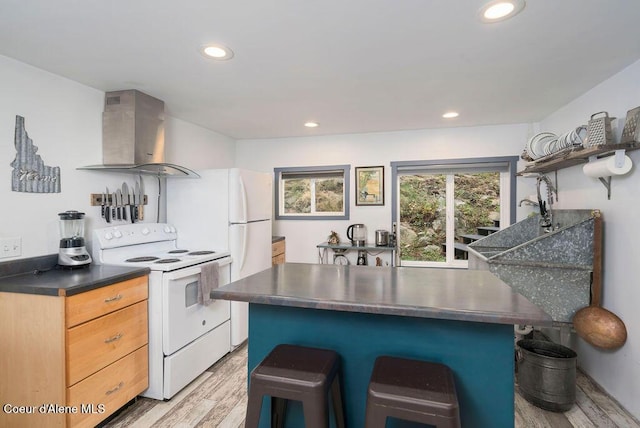 7547 W Channel Ln, Rathdrum, ID 83858 - kitchen with white electric range, wall chimney exhaust hood, a kitchen breakfast bar, dark countertops, and recessed lighting