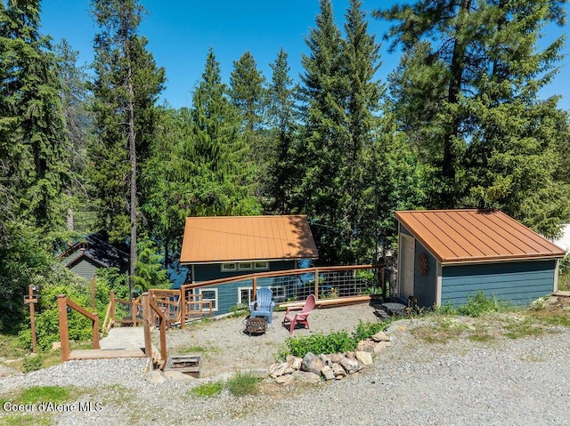 7547 W Channel Ln, Rathdrum, ID 83858 - view of front of property with a standing seam roof, metal roof, an outdoor fire pit, an outbuilding, and a view of trees