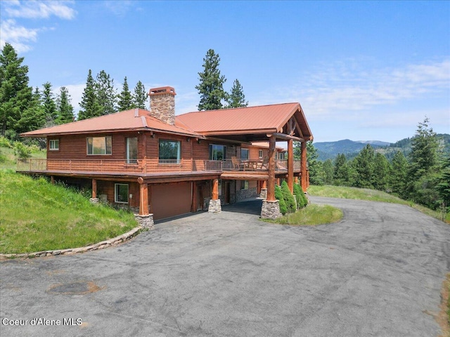 5239 E Dodd Rd, Hayden, ID 83835 - log-style house featuring a chimney, driveway, a garage, stone siding, and metal roof