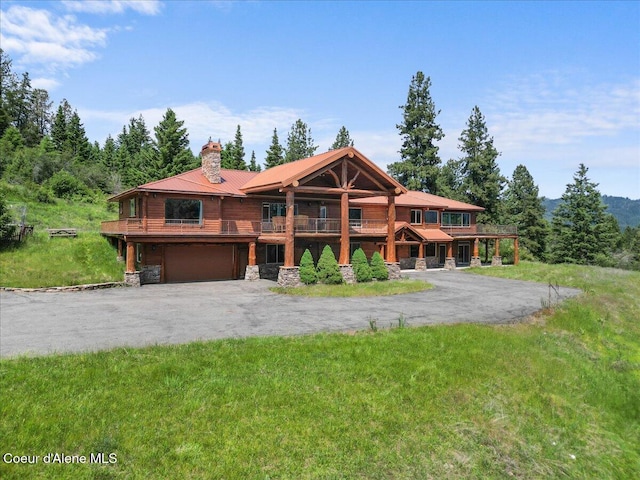 5239 E Dodd Rd, Hayden, ID 83835 - cabin with driveway, a chimney, an attached garage, and stone siding