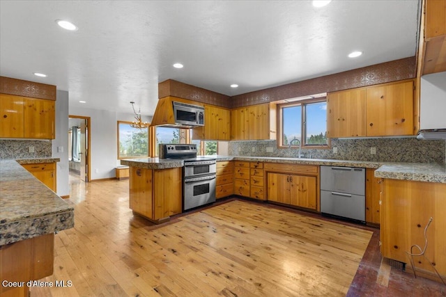 5239 E Dodd Rd, Hayden, ID 83835 - kitchen featuring appliances with stainless steel finishes, tasteful backsplash, brown cabinets, light wood-style floors, and recessed lighting