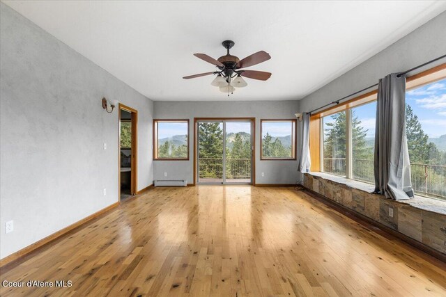 5239 E Dodd Rd, Hayden, ID 83835 - unfurnished sunroom featuring a baseboard heating unit, wood-type flooring, and baseboards