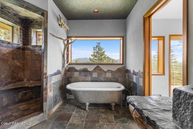 5239 E Dodd Rd, Hayden, ID 83835 - bathroom with stone tile flooring, a freestanding tub, a walk in shower, and a baseboard heating unit