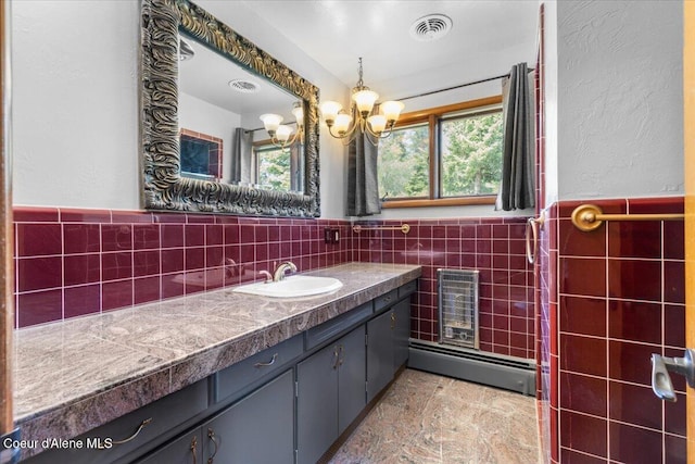 5239 E Dodd Rd, Hayden, ID 83835 - bathroom featuring tile walls, vanity, a baseboard radiator, a wainscoted wall, and a chandelier