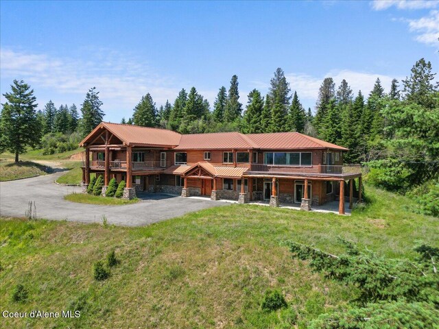 5239 E Dodd Rd, Hayden, ID 83835 - view of front facade with stone siding, asphalt driveway, metal roof, a deck, and a front lawn