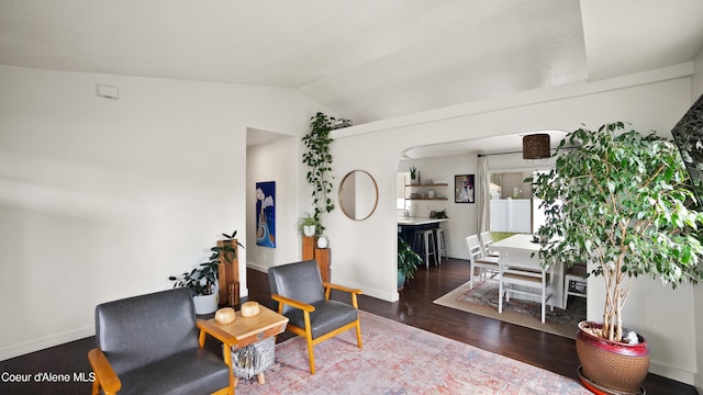 sitting room with vaulted ceiling, wood finished floors, baseboards, and arched walkways