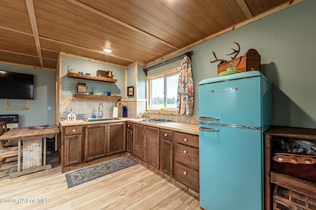 kitchen featuring freestanding refrigerator, a sink, wooden ceiling, light wood-style floors, and backsplash