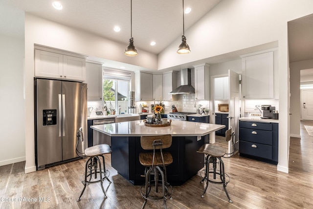 1769 N Chetco Dr, Post Falls, ID 83854 - kitchen with appliances with stainless steel finishes, wall chimney range hood, a kitchen breakfast bar, decorative backsplash, and recessed lighting