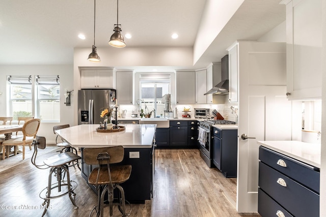 1769 N Chetco Dr, Post Falls, ID 83854 - kitchen featuring stainless steel appliances, wall chimney exhaust hood, a breakfast bar area, light countertops, and decorative light fixtures