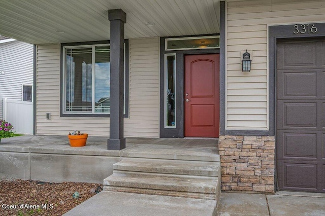 3316 N Van Winkle St, Post Falls, ID 83854 - doorway to property featuring a porch, stone siding, and a garage