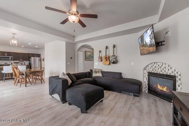 3316 N Van Winkle St, Post Falls, ID 83854 - living room featuring light wood-type flooring, arched walkways, ceiling fan, and a tiled fireplace