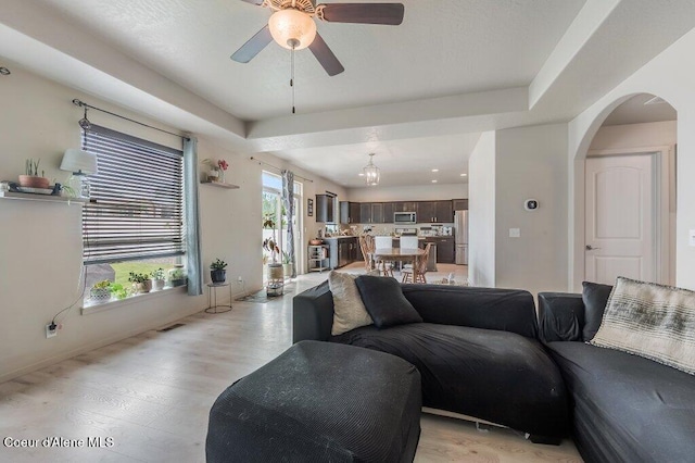 3316 N Van Winkle St, Post Falls, ID 83854 - living room featuring a ceiling fan, light wood-type flooring, arched walkways, and baseboards