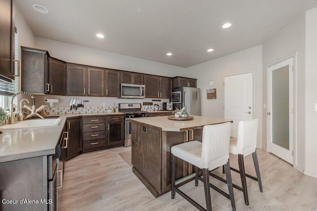 3316 N Van Winkle St, Post Falls, ID 83854 - kitchen featuring appliances with stainless steel finishes, a kitchen bar, light wood-type flooring, dark brown cabinets, and recessed lighting
