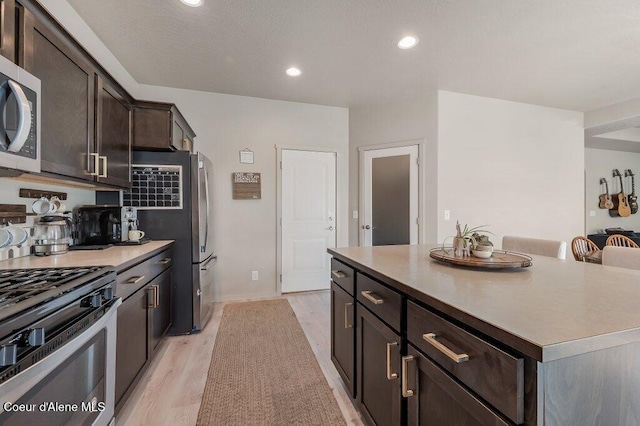 3316 N Van Winkle St, Post Falls, ID 83854 - kitchen featuring appliances with stainless steel finishes, dark brown cabinetry, light wood finished floors, recessed lighting, and a center island
