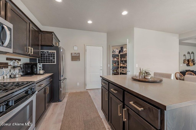3316 N Van Winkle St, Post Falls, ID 83854 - kitchen with stainless steel appliances, dark brown cabinetry, light wood-style floors, recessed lighting, and a kitchen island