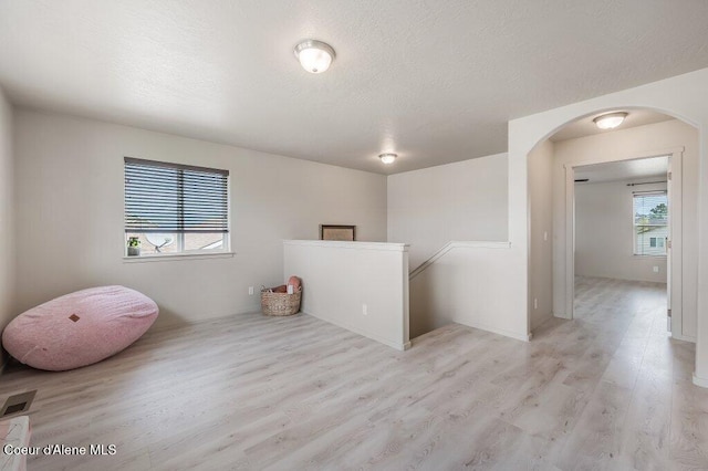 3316 N Van Winkle St, Post Falls, ID 83854 - empty room with light wood-style floors, arched walkways, and a textured ceiling
