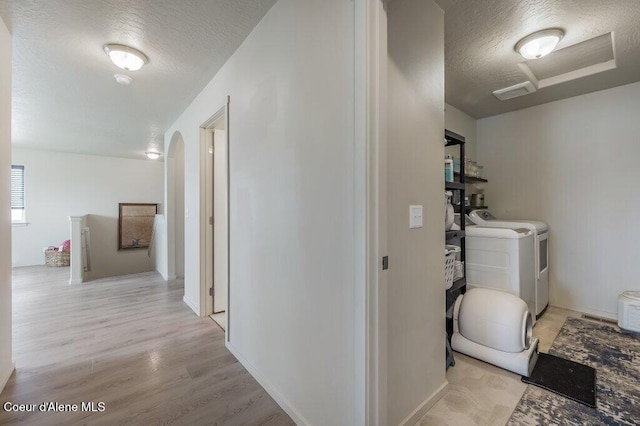 3316 N Van Winkle St, Post Falls, ID 83854 - corridor featuring washing machine and dryer, a textured ceiling, arched walkways, and light wood-style floors