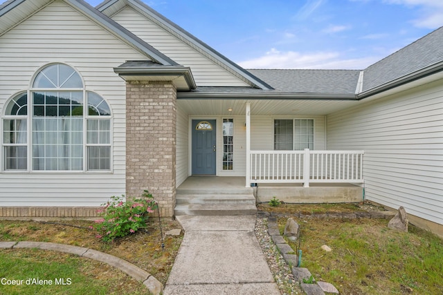 property entrance with covered porch and roof with shingles