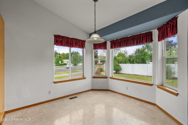 spare room featuring lofted ceiling and baseboards