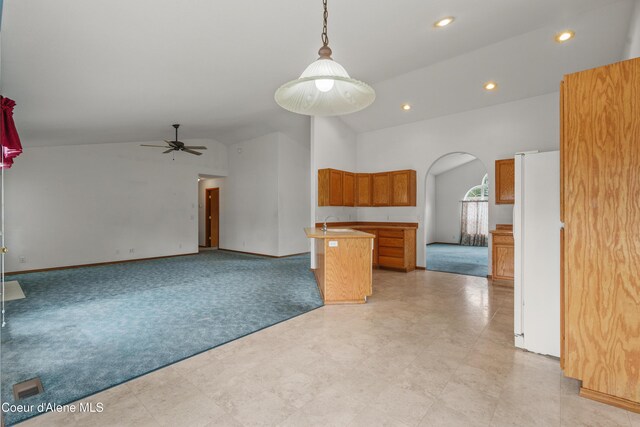 kitchen featuring light carpet, arched walkways, freestanding refrigerator, high vaulted ceiling, and open floor plan