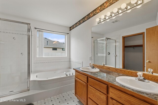 bathroom with a stall shower, a garden tub, double vanity, a spacious closet, and tile patterned floors