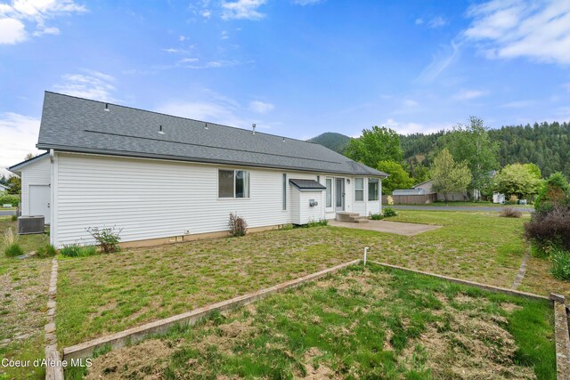 back of house featuring a patio, a lawn, a shingled roof, central AC, and entry steps
