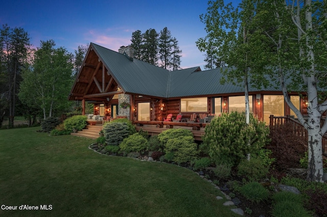 271 W Shore Ln, Sandpoint, ID 83864 - back of property at dusk with log siding, a chimney, a lawn, and metal roof