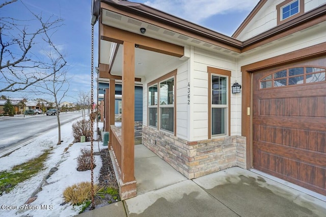 4362 N Meadow Ranch Ave, Coeur Dalene, ID 83815 - snow covered property entrance featuring stone siding and a porch