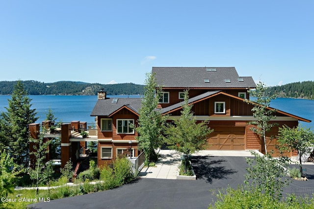 view of front of home with a water view, a chimney, board and batten siding, and a wooded view
