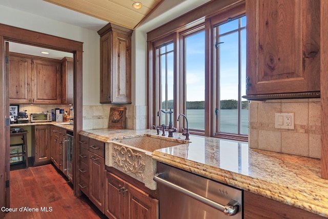 kitchen with stainless steel dishwasher, tasteful backsplash, light stone counters, a sink, and dark wood-style floors