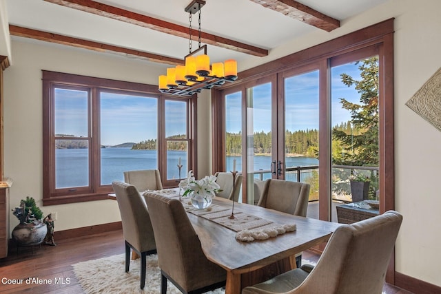 dining room featuring a chandelier, beam ceiling, baseboards, a water view, and wood finished floors